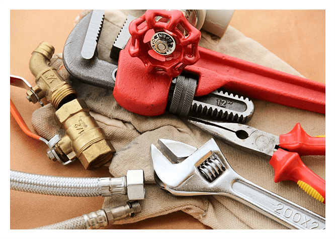 A pair of wrenches and other tools are laying on the table.